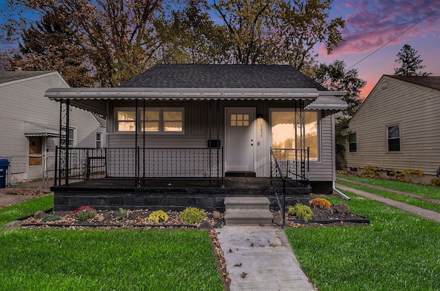 bungalow featuring covered porch and a lawn