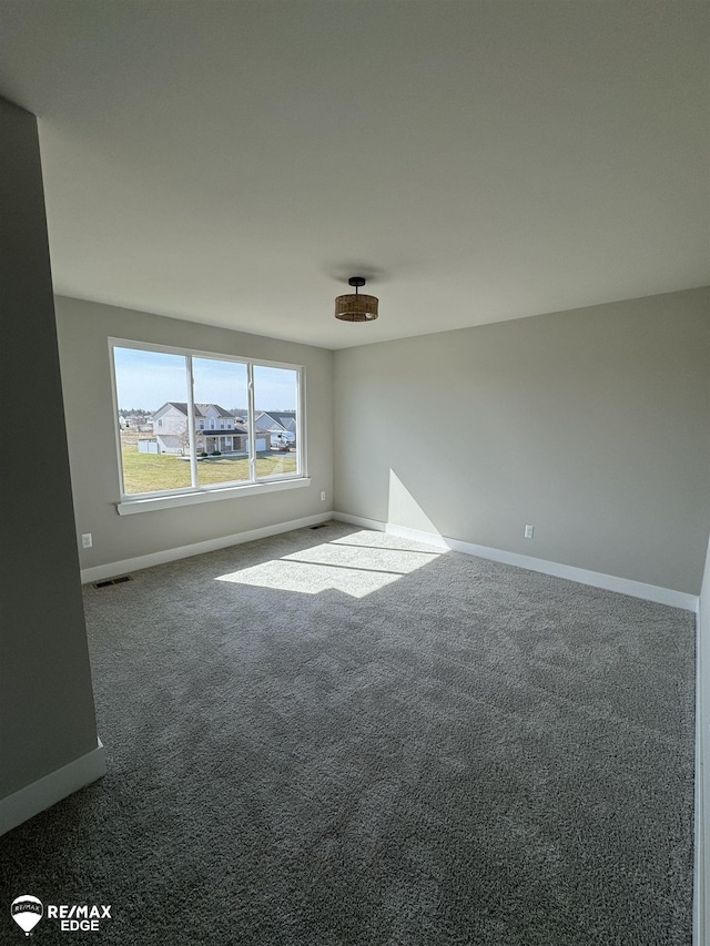 unfurnished room featuring carpet, visible vents, and baseboards