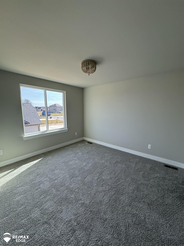 unfurnished room featuring carpet, visible vents, and baseboards