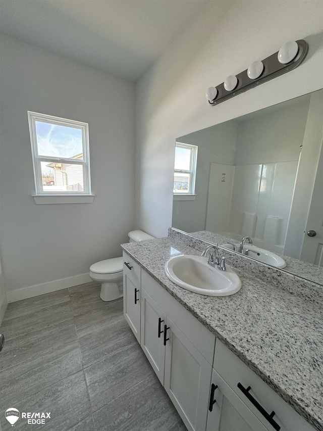 bathroom with toilet, vanity, and baseboards