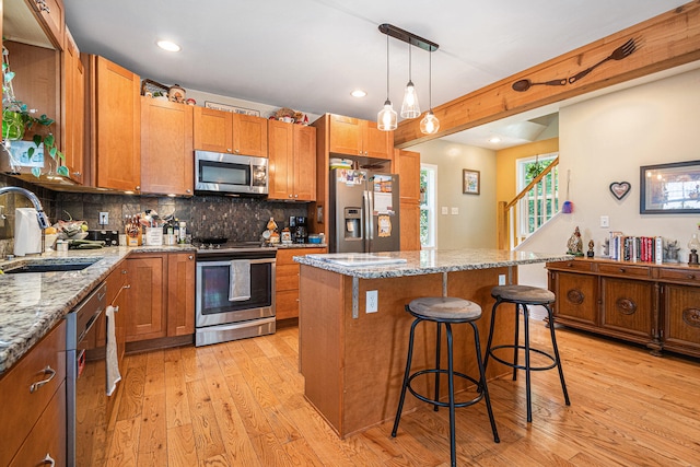 kitchen with light stone counters, sink, light hardwood / wood-style floors, and appliances with stainless steel finishes