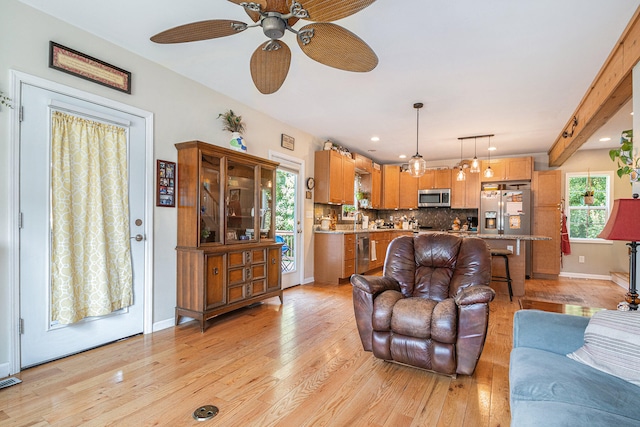 living room featuring beamed ceiling, ceiling fan, light hardwood / wood-style floors, and sink