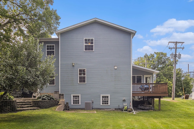 rear view of property with a lawn, central air condition unit, and a deck