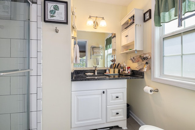 bathroom with plenty of natural light, vanity, a shower with shower door, and tile patterned flooring