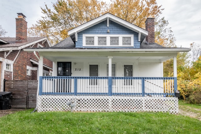 rear view of house featuring a yard and covered porch