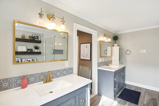 bathroom featuring a sink, wood finished floors, crown molding, and a tile shower