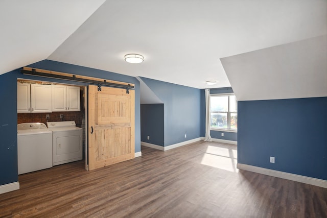 clothes washing area featuring baseboards, a barn door, washer and dryer, dark wood-style floors, and cabinet space