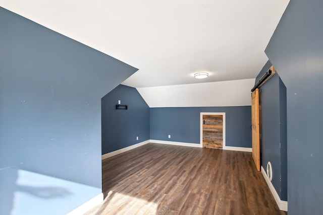 bonus room featuring a barn door, wood finished floors, baseboards, and lofted ceiling