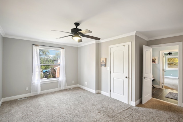 unfurnished bedroom with visible vents, multiple windows, carpet, and ornamental molding