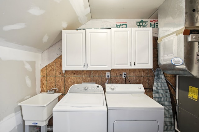 clothes washing area with washer and clothes dryer, cabinet space, and a sink