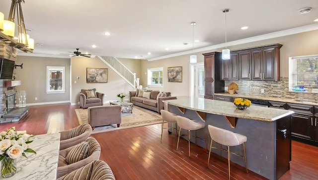 kitchen featuring tasteful backsplash, a center island, open floor plan, a kitchen bar, and a stone fireplace