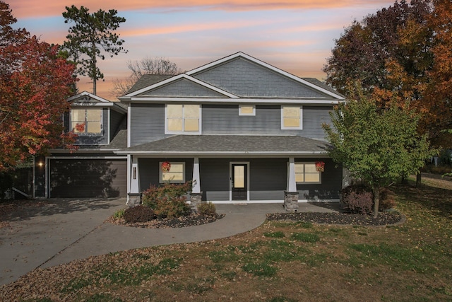 view of front facade featuring a front lawn, an attached garage, covered porch, and driveway