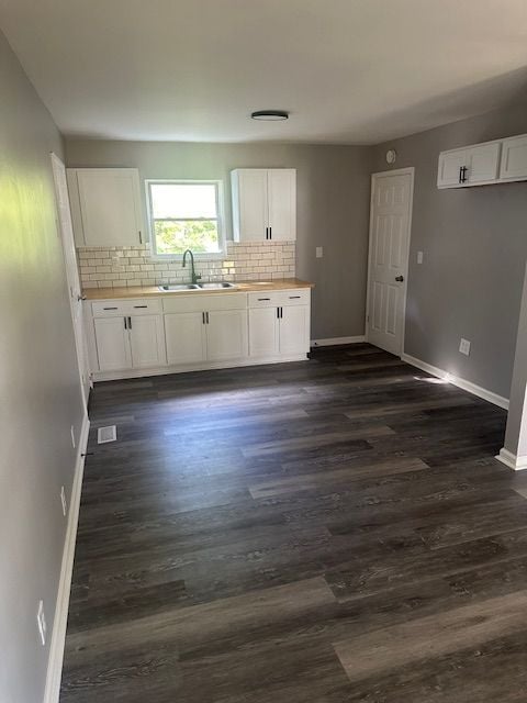 kitchen with white cabinets, decorative backsplash, sink, and dark wood-type flooring