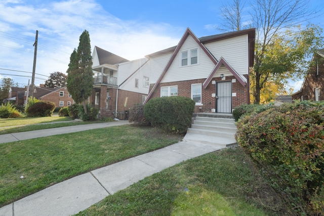 tudor-style house with a balcony and a front yard