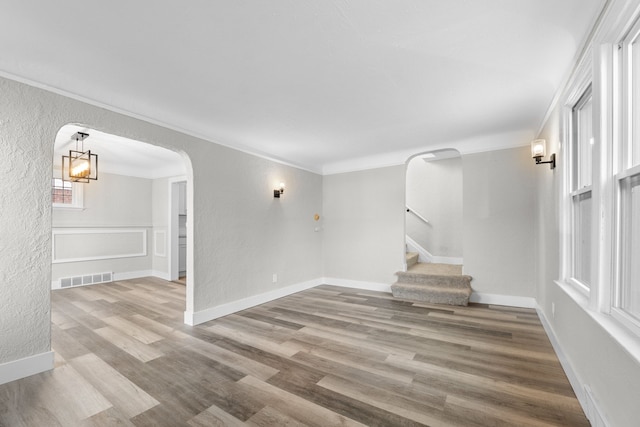 spare room with a chandelier, light hardwood / wood-style floors, and ornamental molding