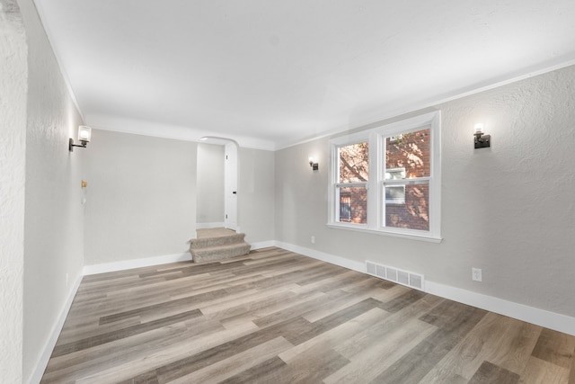 unfurnished room with light wood-type flooring and crown molding