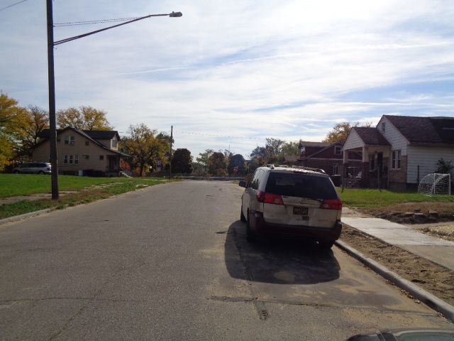 view of road featuring sidewalks, a residential view, curbs, and street lights
