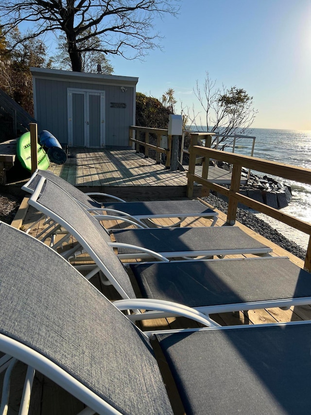 exterior space with a deck with water view and a beach view