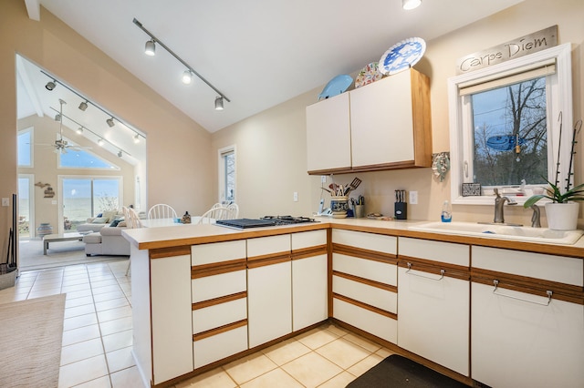 kitchen featuring white cabinets, ceiling fan, sink, and vaulted ceiling