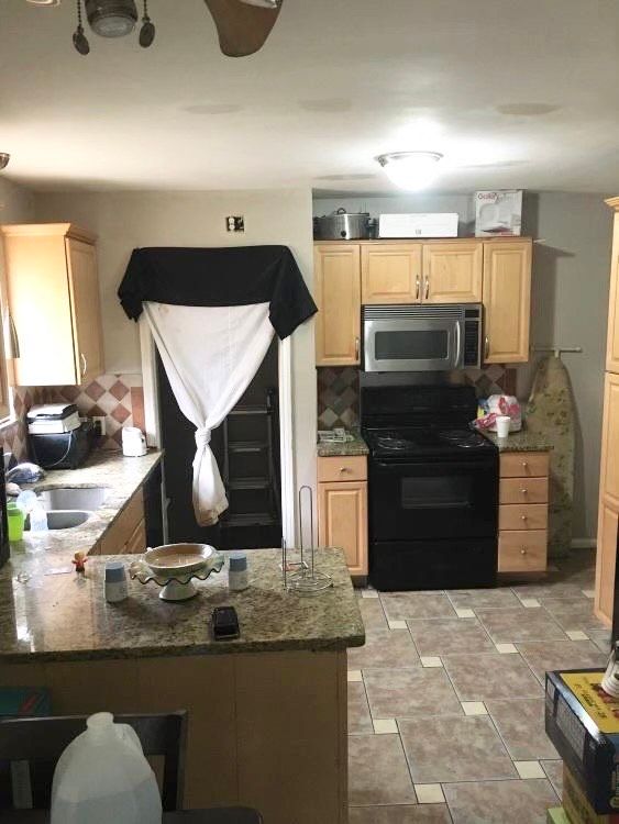 kitchen with electric range, sink, backsplash, kitchen peninsula, and dark stone counters