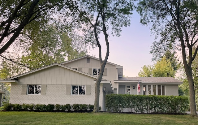 view of front of house featuring brick siding and a front yard