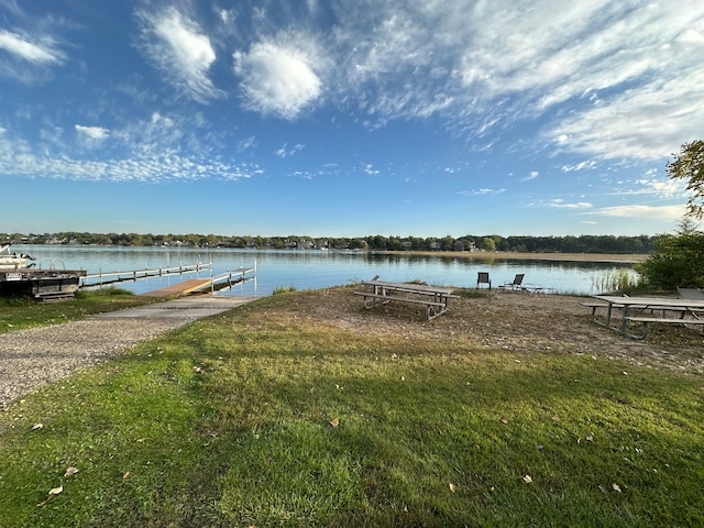 view of dock with a lawn and a water view