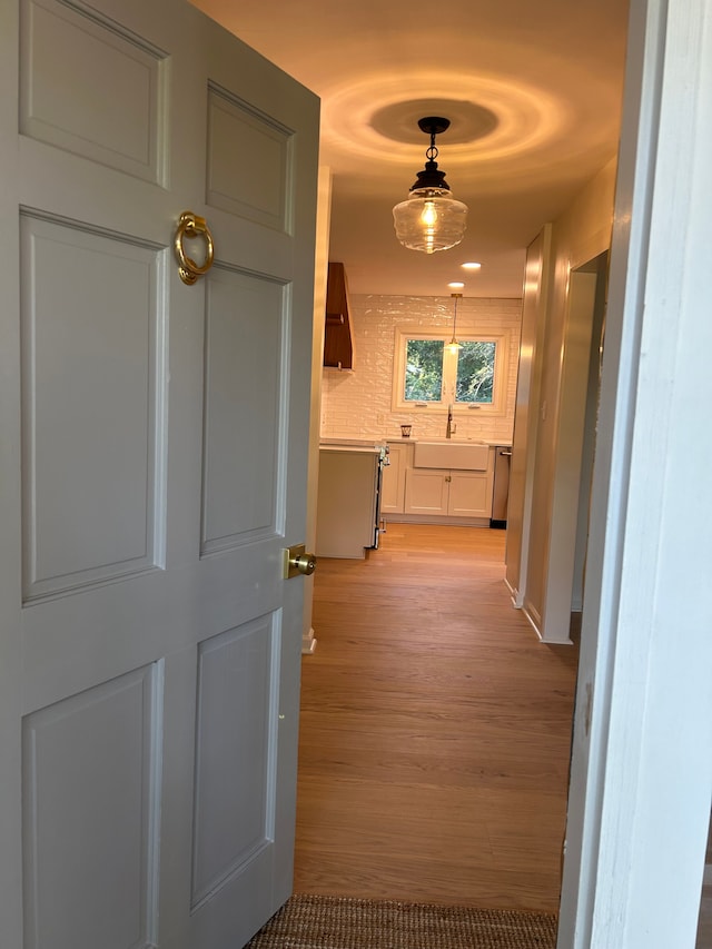 corridor featuring light wood finished floors and a sink