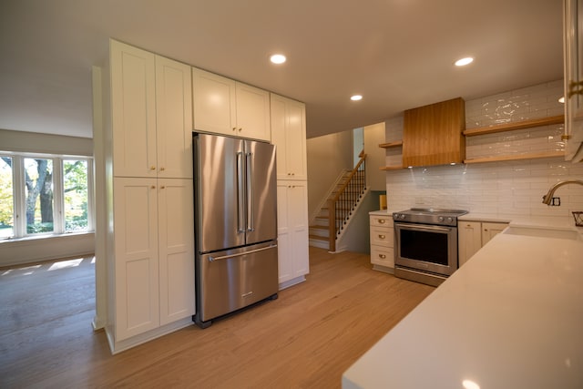 kitchen featuring a sink, open shelves, light wood-style floors, appliances with stainless steel finishes, and white cabinets