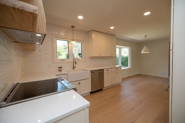 kitchen featuring range hood, a sink, stainless steel appliances, white cabinets, and backsplash