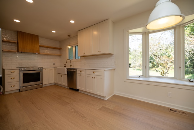 kitchen featuring visible vents, open shelves, a sink, stainless steel appliances, and light wood-style floors