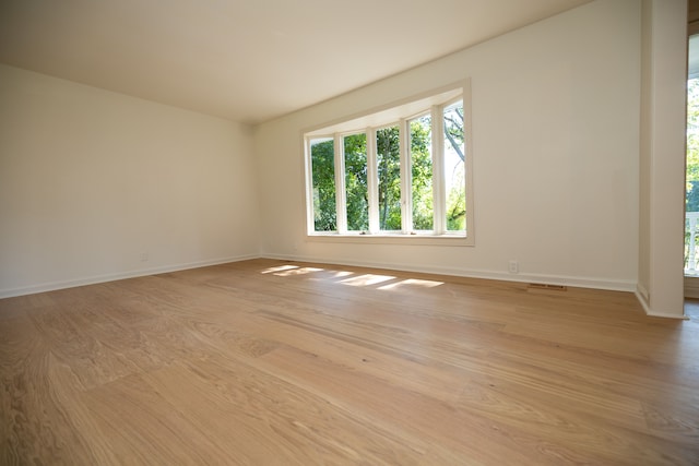 unfurnished room featuring baseboards, visible vents, and light wood finished floors