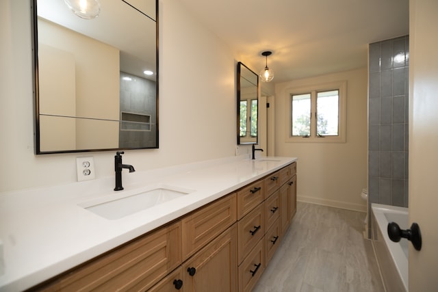 bathroom featuring toilet, a sink, double vanity, baseboards, and a bathtub