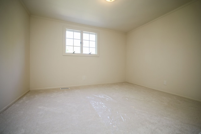 carpeted spare room featuring visible vents, baseboards, and ornamental molding