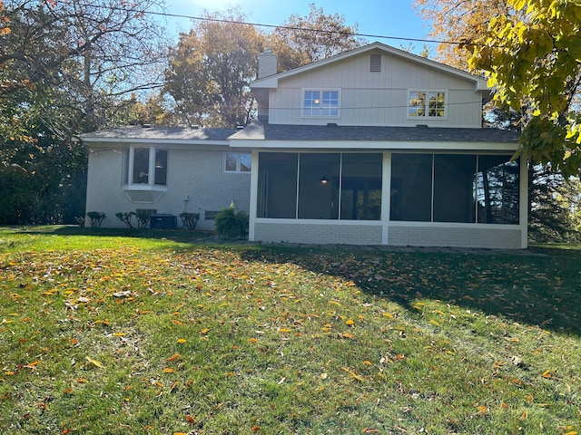 rear view of property with a yard, brick siding, a chimney, and a sunroom