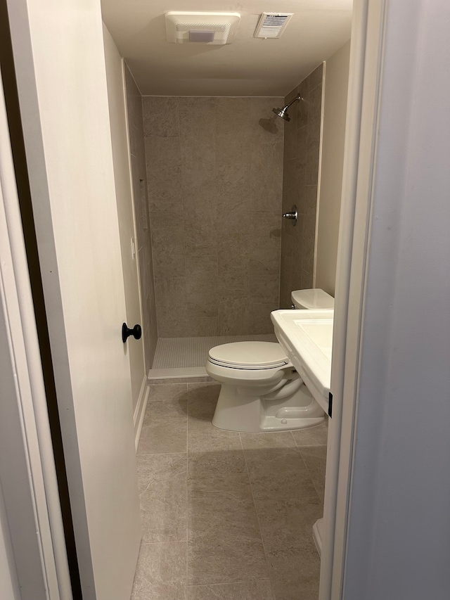 bathroom featuring tile patterned floors, visible vents, toilet, a stall shower, and a sink