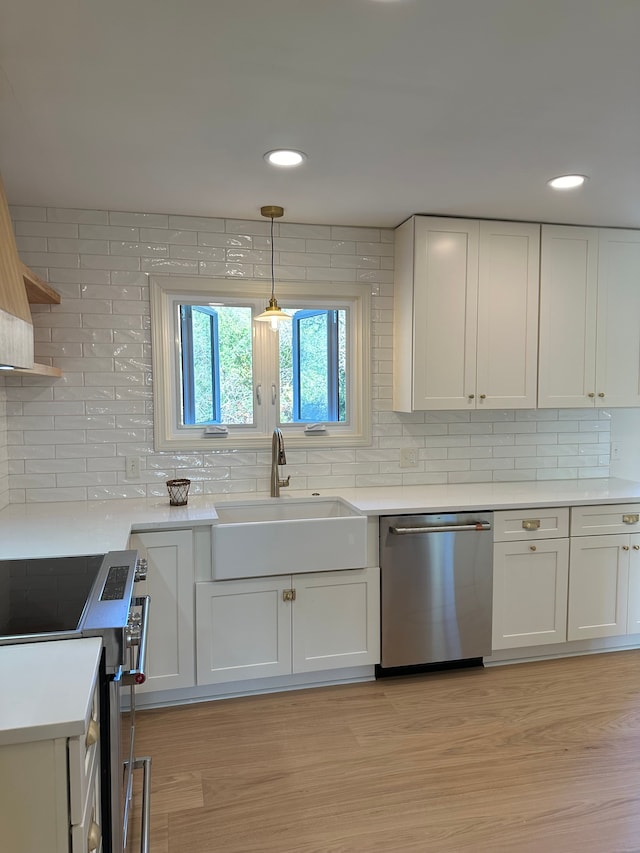 kitchen featuring a sink, white cabinetry, appliances with stainless steel finishes, light wood finished floors, and light countertops