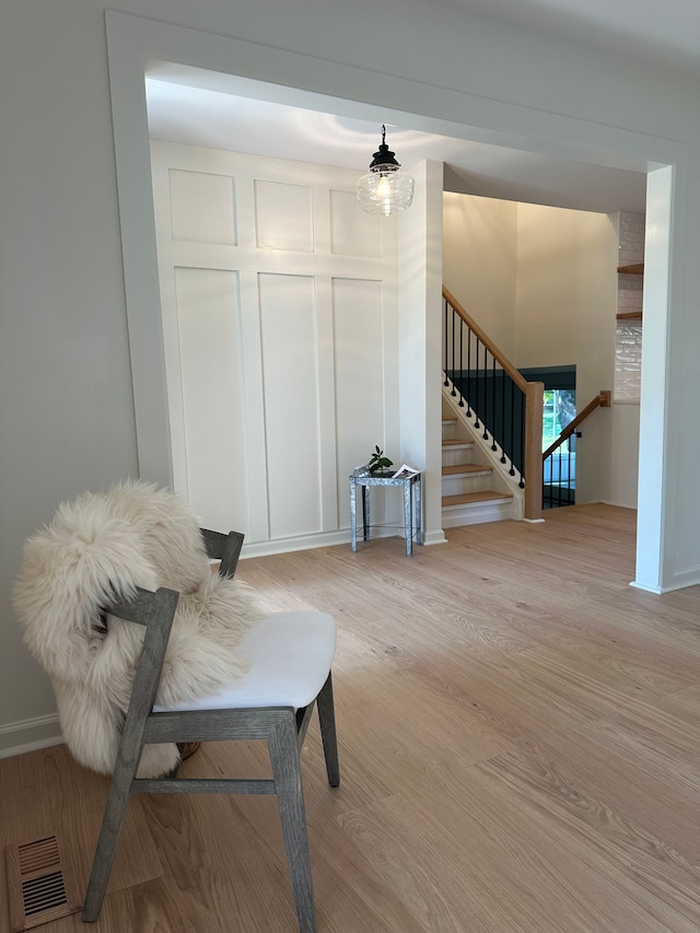 living area featuring visible vents, stairway, light wood-style flooring, and a decorative wall