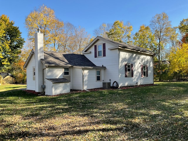 back of property with central AC and a yard