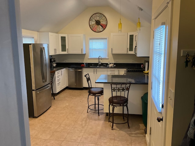 kitchen with appliances with stainless steel finishes, a kitchen breakfast bar, vaulted ceiling, pendant lighting, and white cabinetry