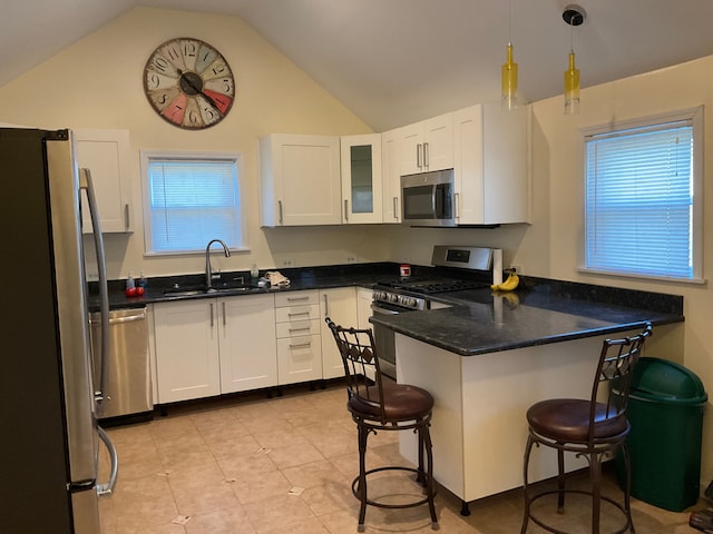 kitchen featuring lofted ceiling, white cabinets, a kitchen breakfast bar, sink, and stainless steel appliances