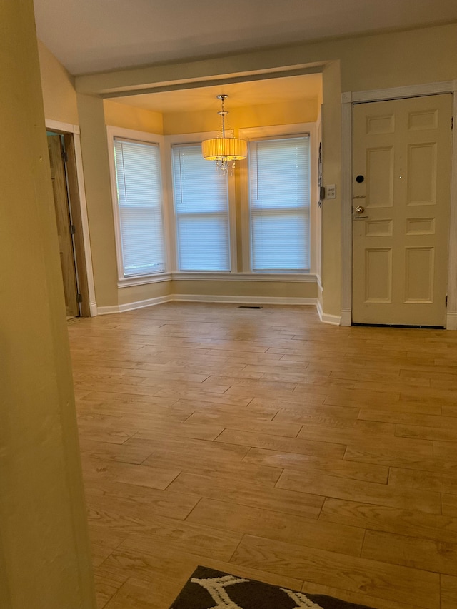 unfurnished dining area with a chandelier and light hardwood / wood-style flooring