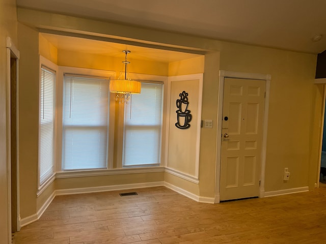 unfurnished dining area featuring light hardwood / wood-style floors and an inviting chandelier