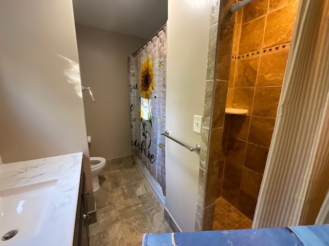 bathroom featuring tiled shower, vanity, and toilet