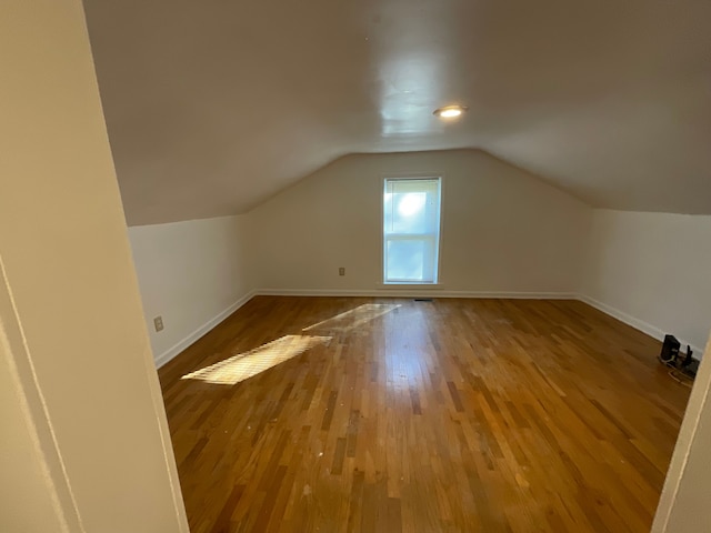 bonus room with hardwood / wood-style flooring and vaulted ceiling