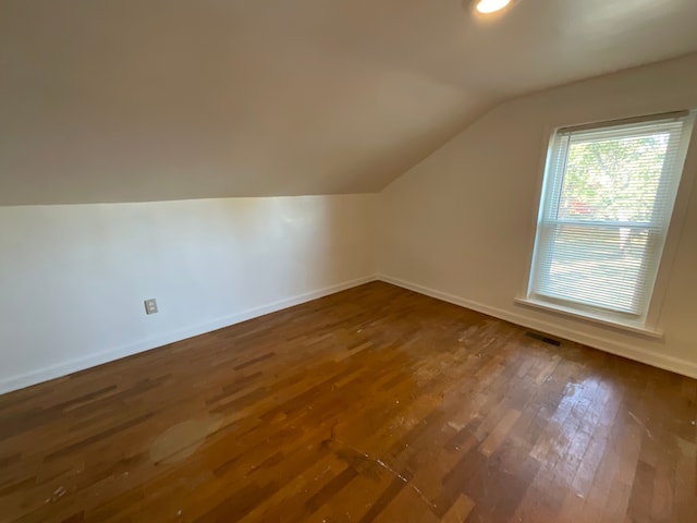 additional living space featuring vaulted ceiling and dark wood-type flooring