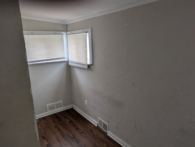 empty room with dark hardwood / wood-style flooring and crown molding