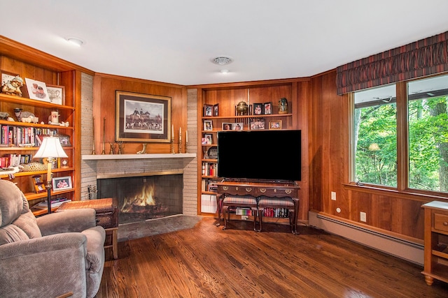 living room featuring built in shelves, a baseboard radiator, a brick fireplace, wood-type flooring, and wooden walls