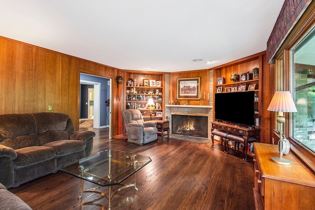 living room featuring a fireplace, dark hardwood / wood-style flooring, built in features, and wooden walls