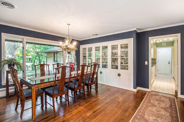 dining area featuring dark hardwood / wood-style flooring, ornamental molding, and an inviting chandelier