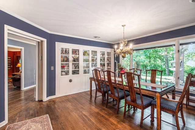 dining room with dark hardwood / wood-style flooring, ornamental molding, and an inviting chandelier